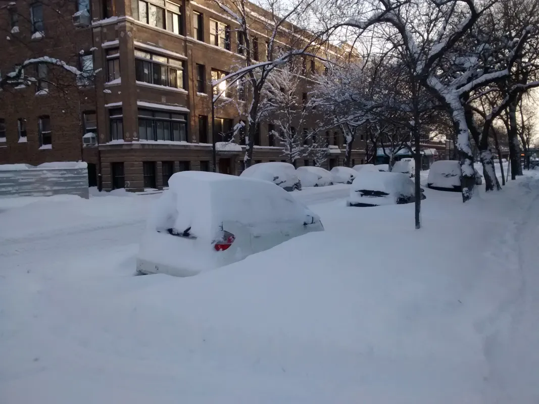 Cars buried in snow on a city street after a snowstorm