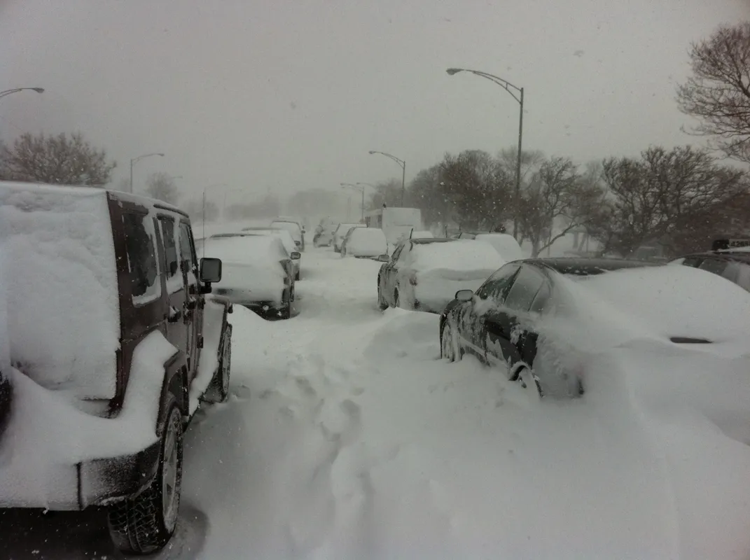 Cars stuck in deep snow on a city road during a blizzard